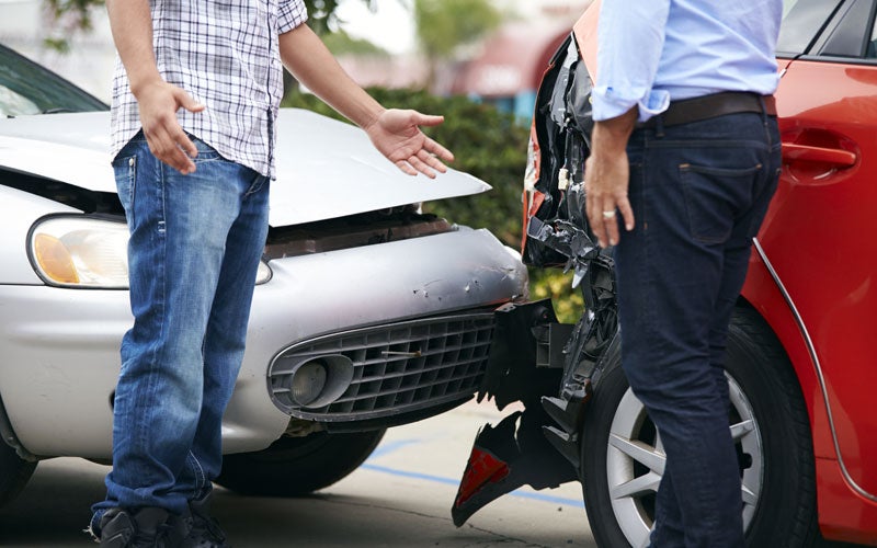 two people standing outside of cars after accident