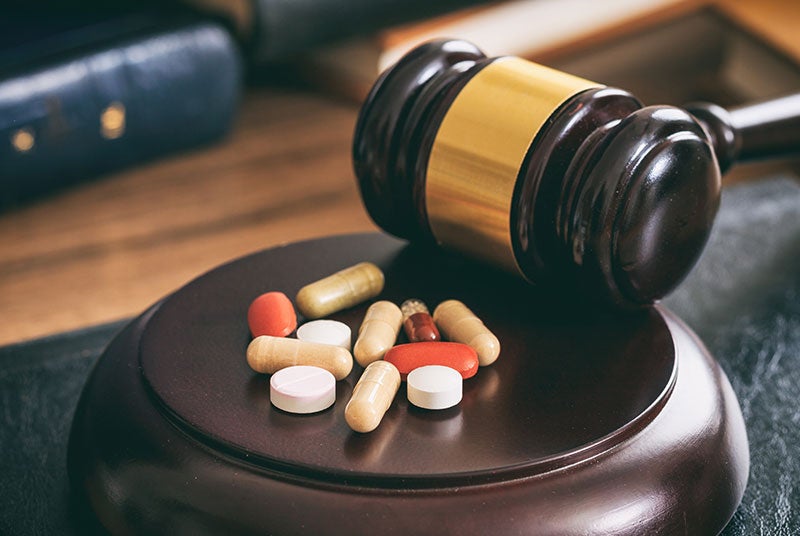 A pile of various drugs ona desk next to gavel