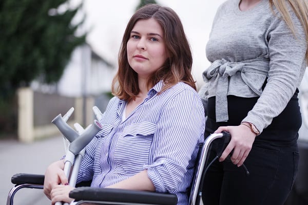 Woman being pushed in a wheelchair by another woman after suffering a serious injury