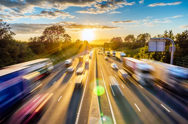 heavy traffic moving at speed on a highway at sunset