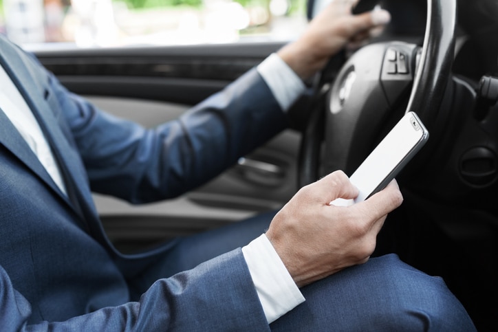 A man texting on his phone while driving his car.