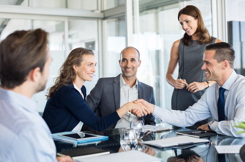 Group of professional business owners and their lawyers shaking hands after completing a deal